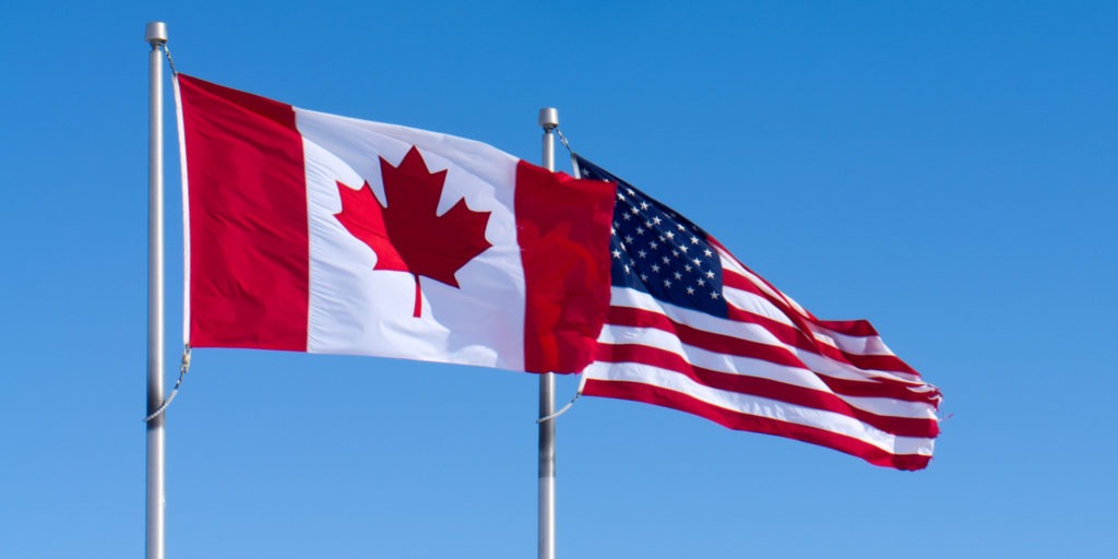 The American and Canadian flags fly in the breeze.